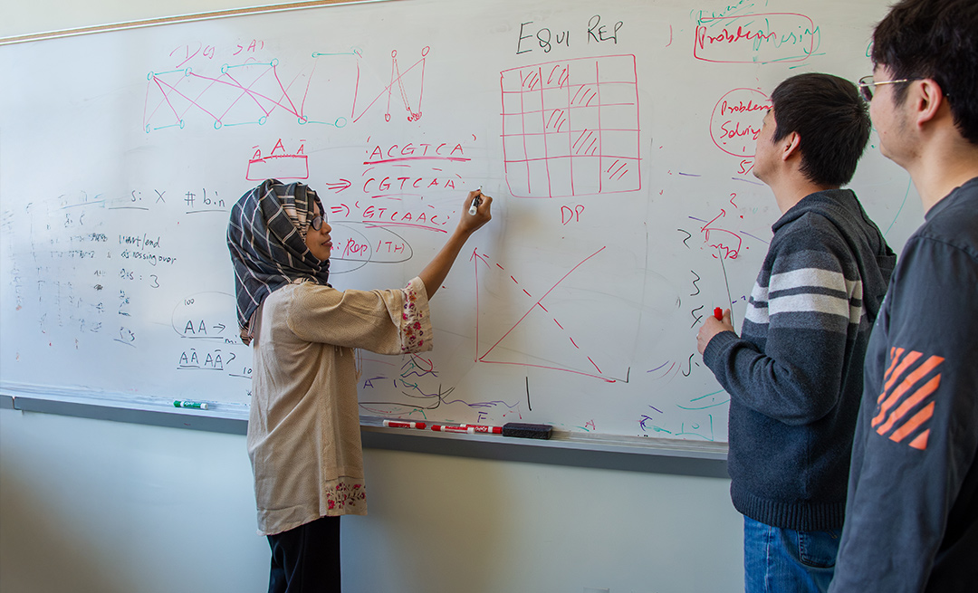four people look at a whiteboard