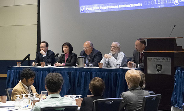 Five panelists sit at the front of the conference room