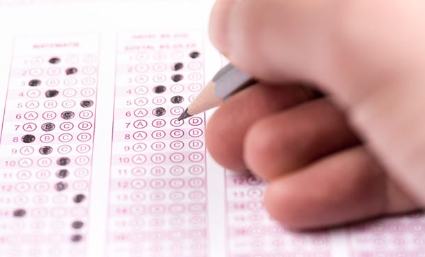 person marking a test answer form with a pencil