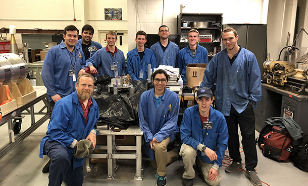 A group of students pose with their work in a lab.