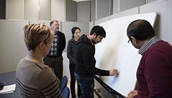 Researchers collaborate around a white board