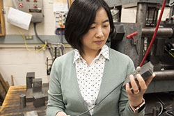 Jing Yang examines a piece of lab equipment 